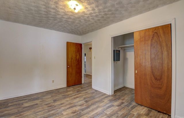 unfurnished bedroom with a textured ceiling, dark hardwood / wood-style flooring, and a closet