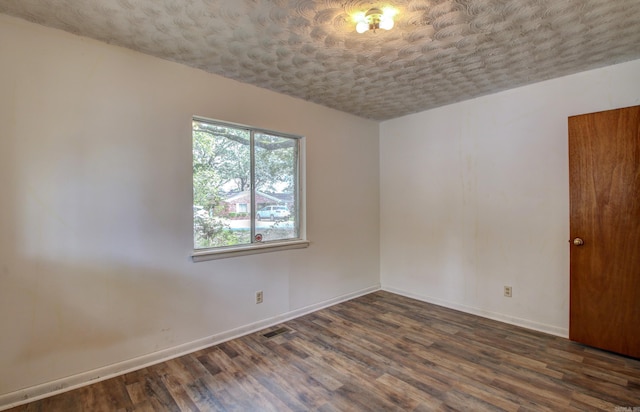 unfurnished room featuring a textured ceiling and dark hardwood / wood-style flooring