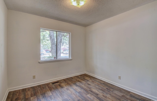 empty room featuring a textured ceiling and dark hardwood / wood-style flooring