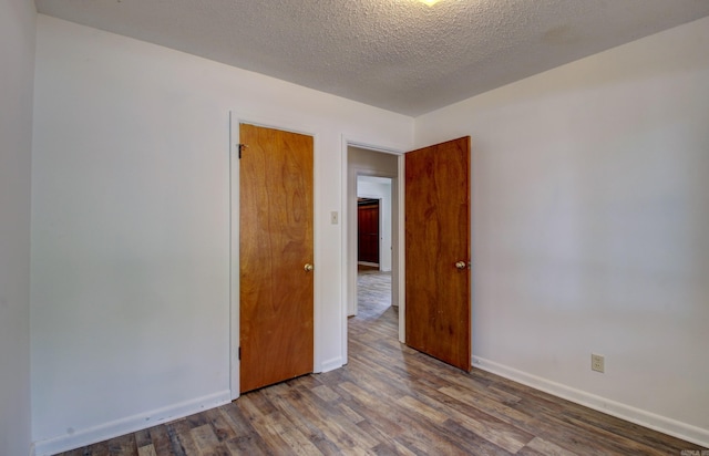 spare room featuring a textured ceiling and dark hardwood / wood-style flooring