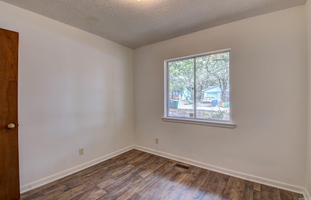 empty room featuring a textured ceiling and dark hardwood / wood-style floors