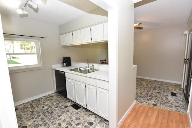 kitchen with light wood-type flooring, white cabinetry, black dishwasher, and sink