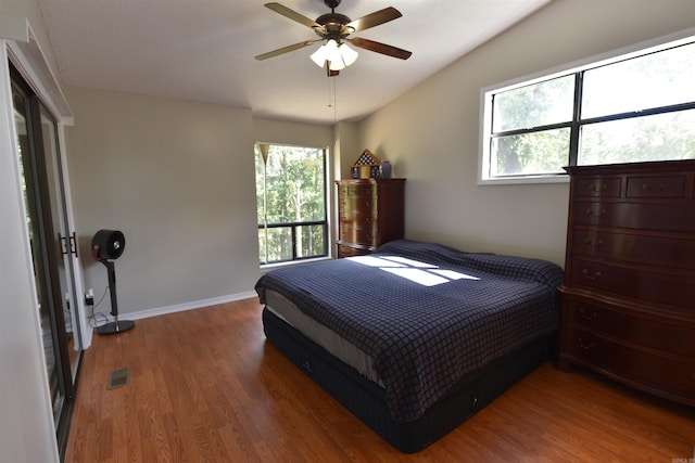 bedroom featuring ceiling fan, hardwood / wood-style floors, and multiple windows