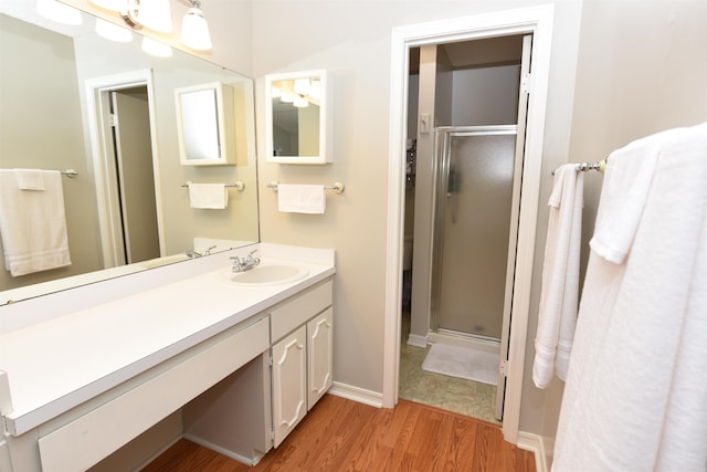 bathroom with walk in shower, vanity, and wood-type flooring