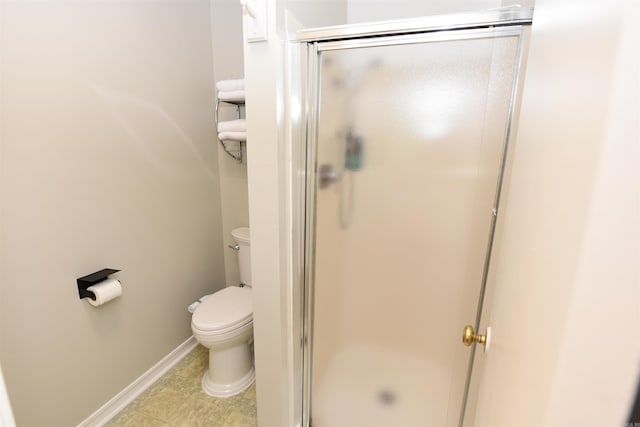 bathroom featuring a shower with door and toilet