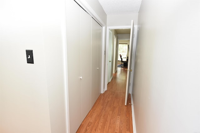 hallway featuring a textured ceiling and light hardwood / wood-style floors