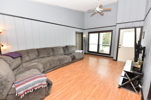 living room with a towering ceiling, ceiling fan, and hardwood / wood-style flooring