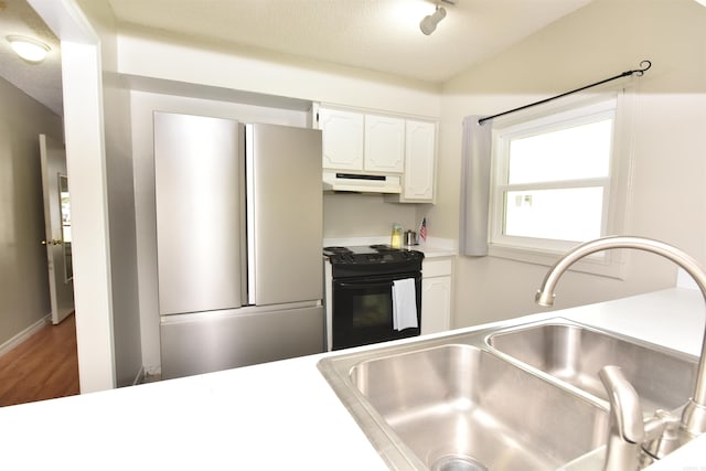 kitchen with white cabinets, stainless steel refrigerator, black range with electric cooktop, hardwood / wood-style flooring, and sink