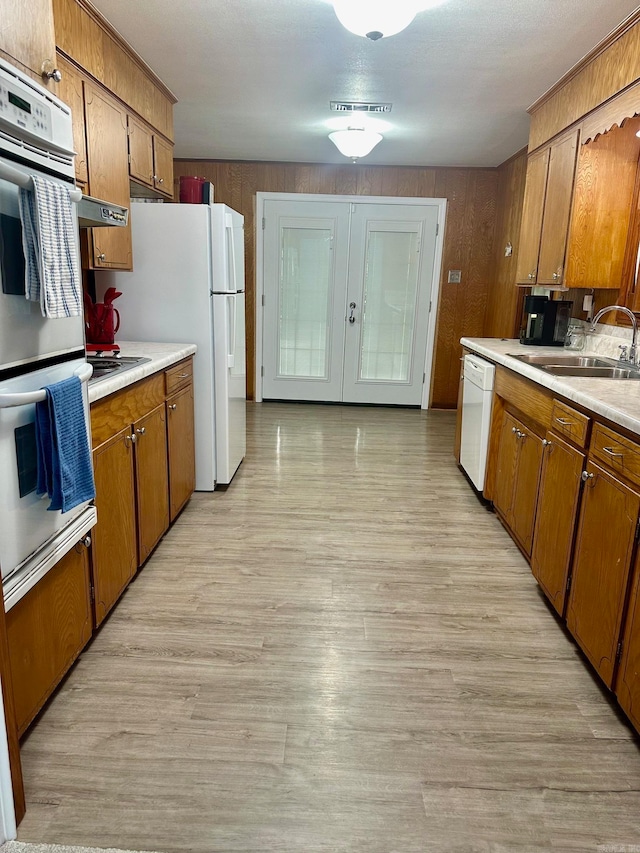 kitchen featuring ventilation hood, light hardwood / wood-style flooring, sink, and white appliances