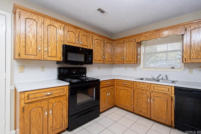 kitchen with light tile patterned flooring, sink, a textured ceiling, and black appliances