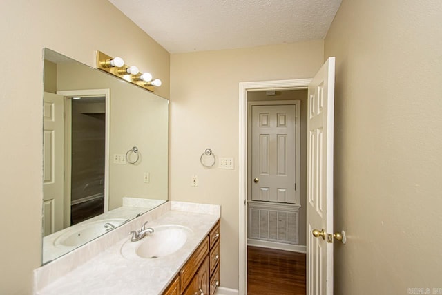 bathroom with hardwood / wood-style floors, a textured ceiling, and vanity