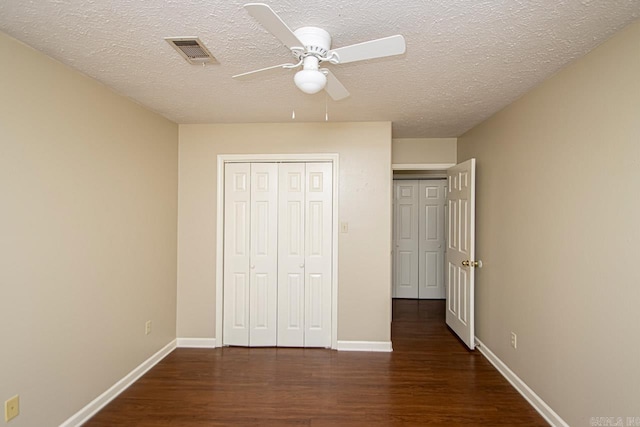 unfurnished bedroom with a closet, ceiling fan, dark hardwood / wood-style floors, and a textured ceiling