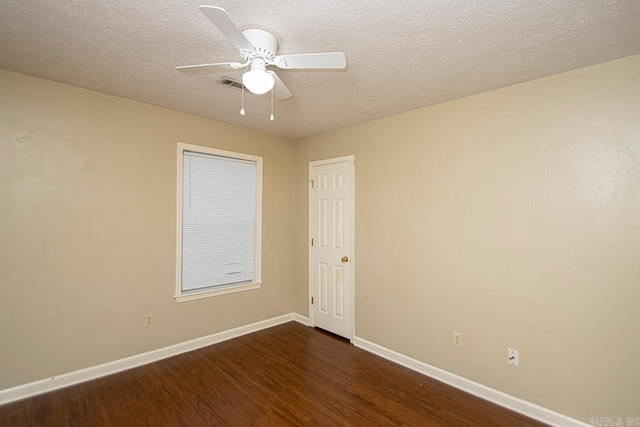 empty room featuring ceiling fan, dark wood-type flooring, and a textured ceiling