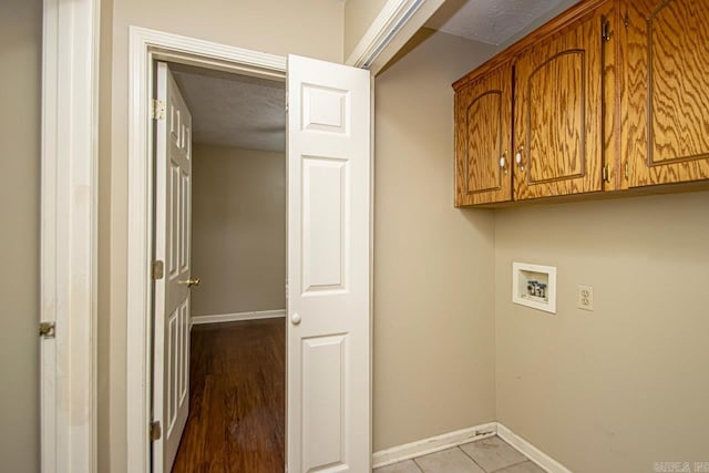 laundry room with washer hookup, cabinets, light tile patterned floors, and a textured ceiling