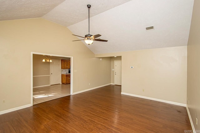 unfurnished room with ceiling fan with notable chandelier, vaulted ceiling, and dark hardwood / wood-style floors