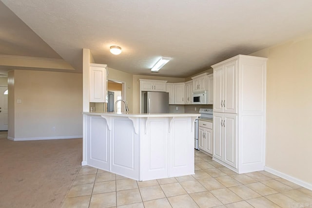 kitchen featuring white cabinets, white appliances, kitchen peninsula, a kitchen bar, and light carpet