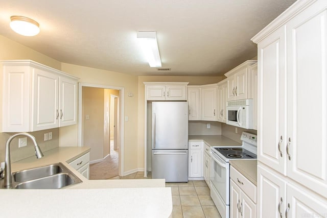 kitchen with a textured ceiling, sink, white cabinets, white appliances, and light tile patterned floors