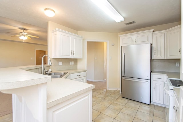 kitchen featuring sink, white cabinets, kitchen peninsula, stainless steel refrigerator, and ceiling fan