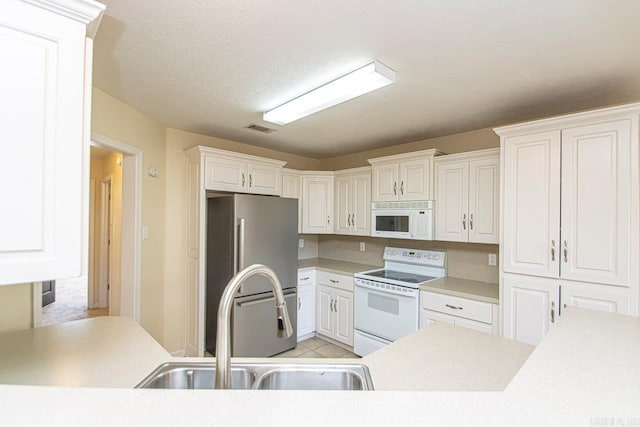 kitchen with white cabinets, a textured ceiling, sink, and white appliances