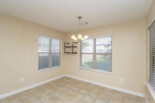 tiled spare room with an inviting chandelier and plenty of natural light