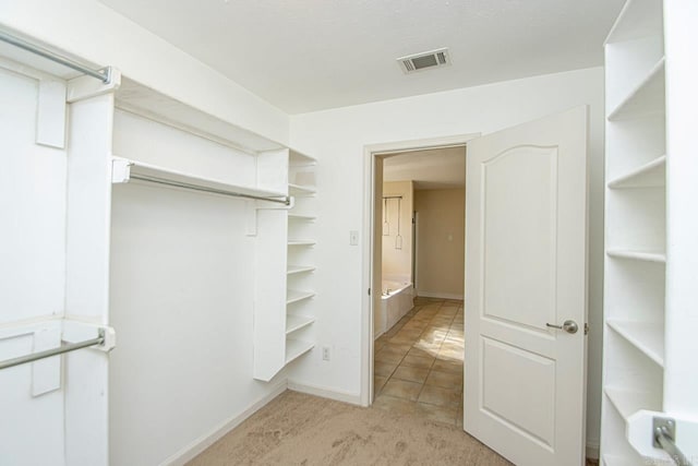 walk in closet featuring light carpet