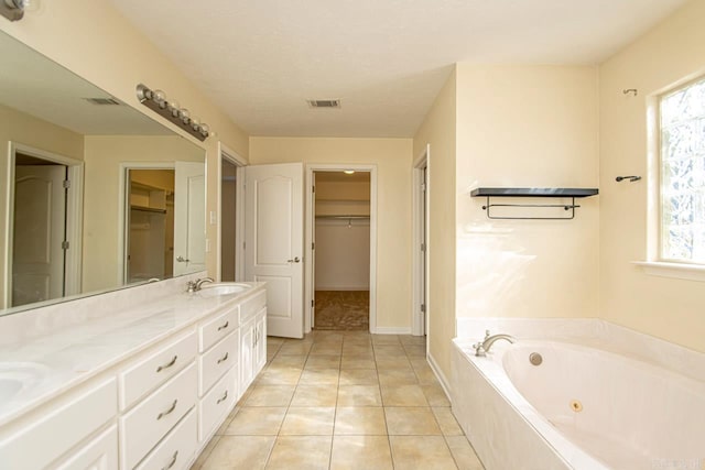 bathroom with vanity, tile patterned floors, and a relaxing tiled tub