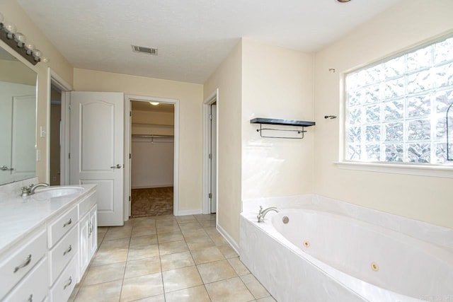 bathroom featuring vanity, a textured ceiling, tile patterned flooring, and a bath