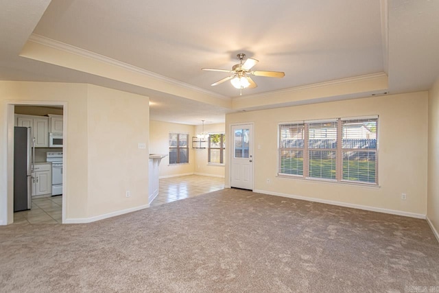 interior space with a raised ceiling, ceiling fan with notable chandelier, and light colored carpet