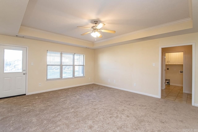 empty room featuring ceiling fan, a raised ceiling, light carpet, and crown molding