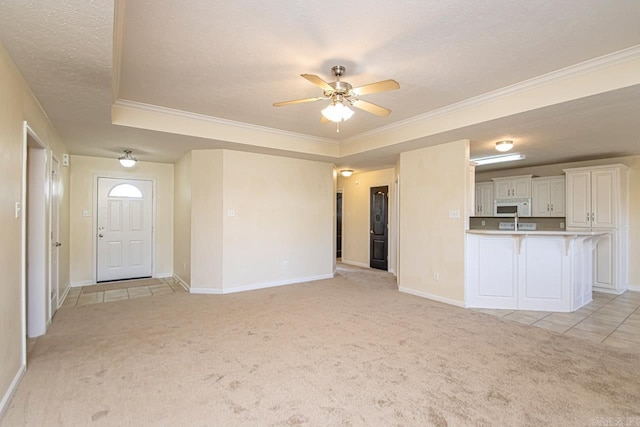 unfurnished living room featuring a textured ceiling, a raised ceiling, light carpet, and ceiling fan