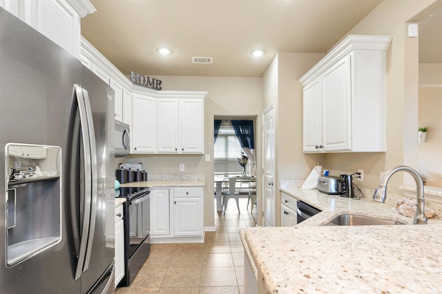 kitchen with light stone counters, white cabinets, light tile patterned floors, stainless steel appliances, and sink