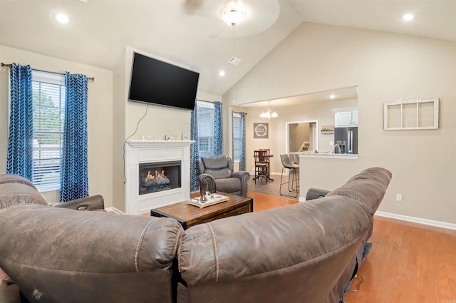 living room with ceiling fan, light hardwood / wood-style flooring, and high vaulted ceiling