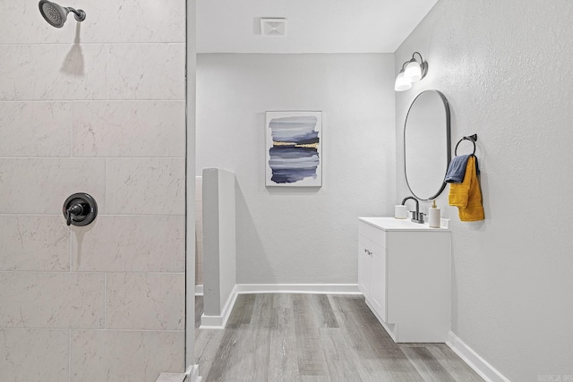 bathroom featuring vanity, a tile shower, and hardwood / wood-style flooring