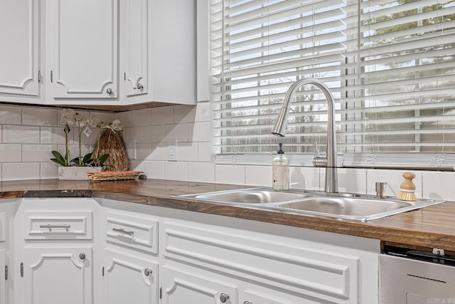 kitchen with backsplash, white cabinetry, and sink