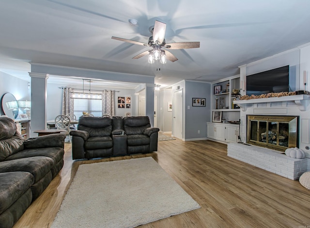 living room with light hardwood / wood-style flooring, a brick fireplace, ceiling fan, and crown molding