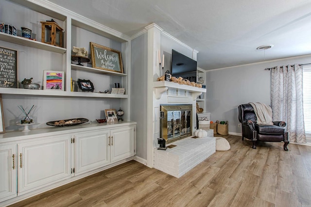 living room featuring a fireplace, ornamental molding, and light hardwood / wood-style flooring