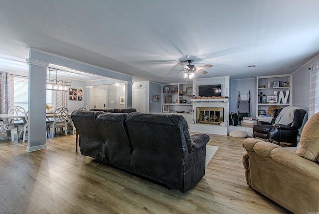 living room featuring built in shelves, ornamental molding, ceiling fan, and light hardwood / wood-style flooring