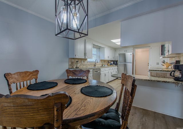 dining space with light wood-type flooring, crown molding, and sink