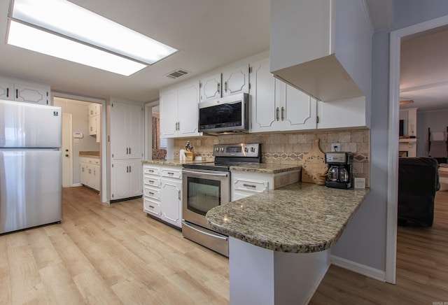 kitchen with kitchen peninsula, white cabinetry, appliances with stainless steel finishes, light hardwood / wood-style floors, and decorative backsplash