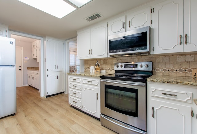 kitchen featuring light stone counters, light hardwood / wood-style flooring, white cabinetry, appliances with stainless steel finishes, and decorative backsplash