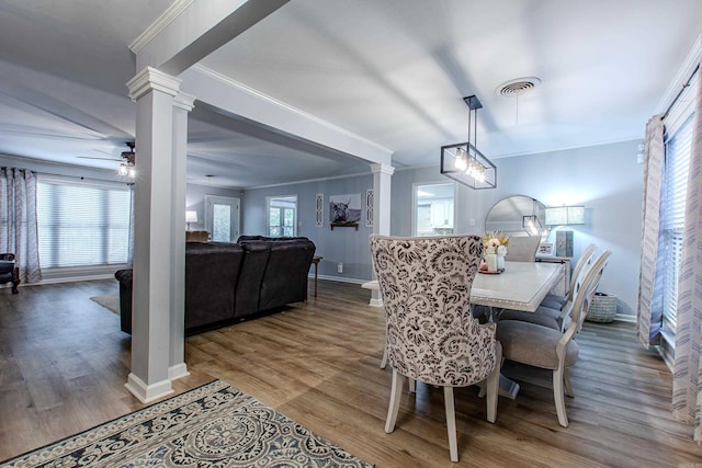 dining area with wood-type flooring, ceiling fan, crown molding, and ornate columns