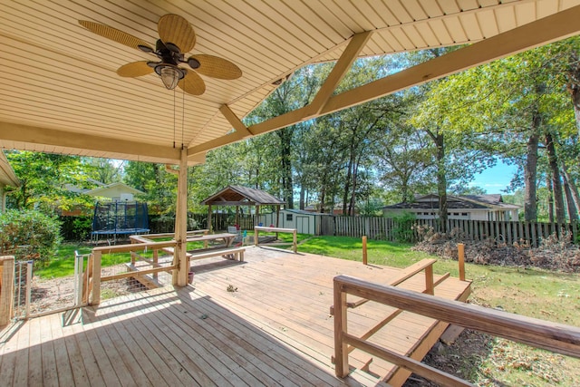 wooden terrace featuring a trampoline, ceiling fan, and a yard