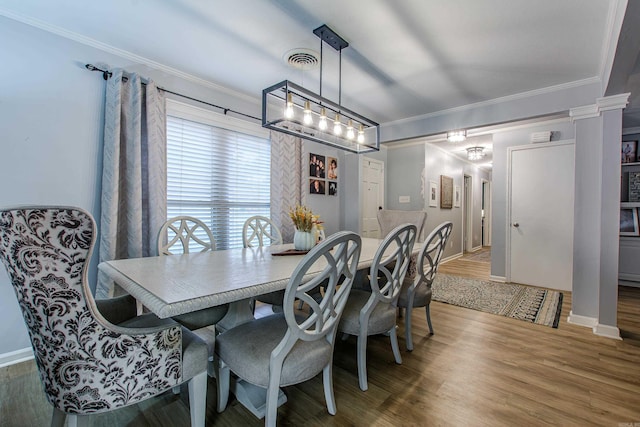 dining room with wood-type flooring, ornamental molding, and ornate columns