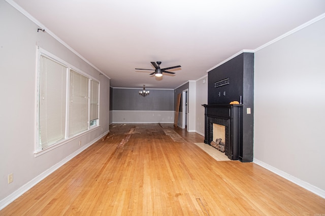 unfurnished living room featuring crown molding, a large fireplace, ceiling fan, and hardwood / wood-style flooring