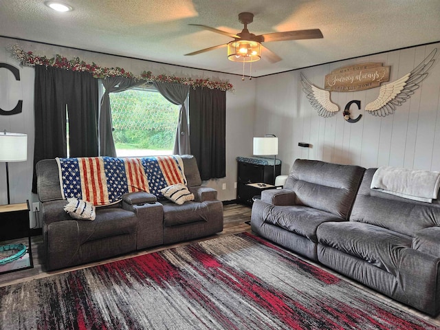 living room featuring wood-type flooring, ceiling fan, and a textured ceiling