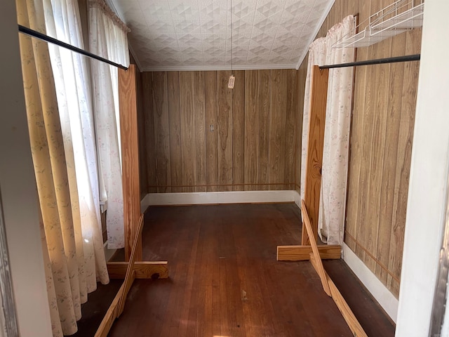 interior space featuring wood walls, dark hardwood / wood-style flooring, and crown molding