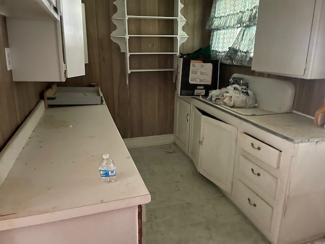 kitchen featuring wooden walls and white cabinetry