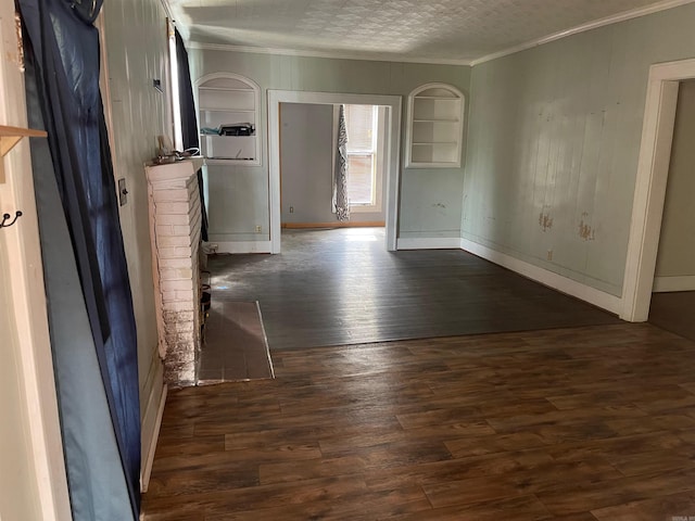 unfurnished room with a textured ceiling, dark wood-type flooring, and crown molding