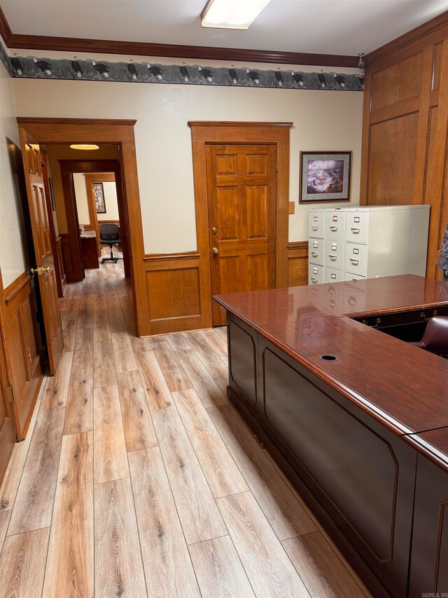 home office with light hardwood / wood-style flooring, wood walls, and ornamental molding