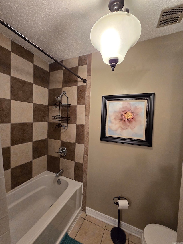 bathroom with tile patterned floors, toilet, a textured ceiling, and tiled shower / bath